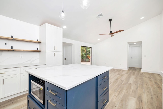 kitchen with vaulted ceiling, ceiling fan, light hardwood / wood-style flooring, white cabinetry, and stainless steel microwave