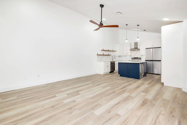 kitchen with white cabinets, light hardwood / wood-style flooring, appliances with stainless steel finishes, decorative light fixtures, and a kitchen island