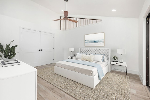 bedroom featuring ceiling fan, a closet, high vaulted ceiling, and light wood-type flooring