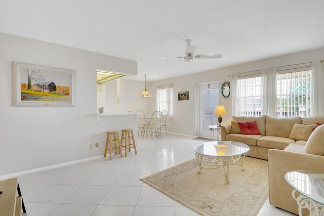 tiled living room featuring a wealth of natural light, ceiling fan, and a textured ceiling