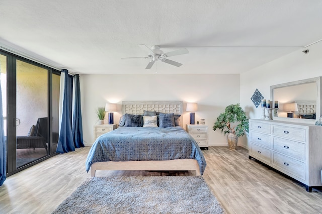 bedroom featuring ceiling fan, light hardwood / wood-style floors, a textured ceiling, and a wall of windows