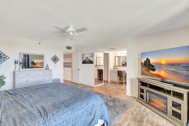 bedroom featuring light wood-type flooring, ensuite bathroom, and ceiling fan