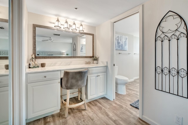 bathroom featuring hardwood / wood-style flooring, ceiling fan, toilet, and vanity