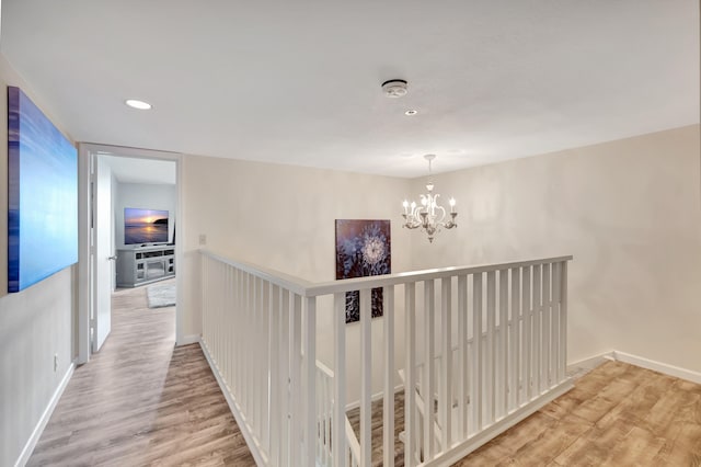 hallway with a notable chandelier and light wood-type flooring