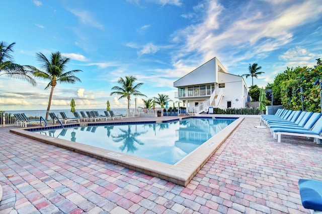 view of swimming pool featuring a water view and a patio area