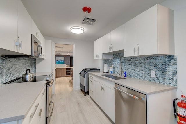 kitchen with sink, white cabinetry, stainless steel appliances, and light wood-type flooring