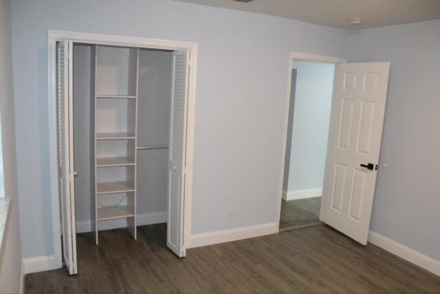 unfurnished bedroom featuring a closet and dark wood-type flooring