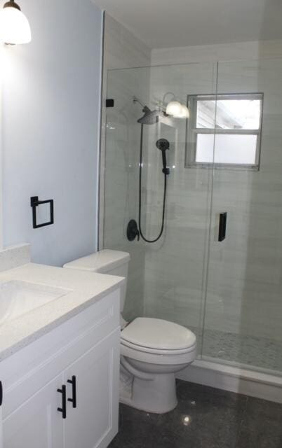 bathroom with walk in shower, vanity, and toilet