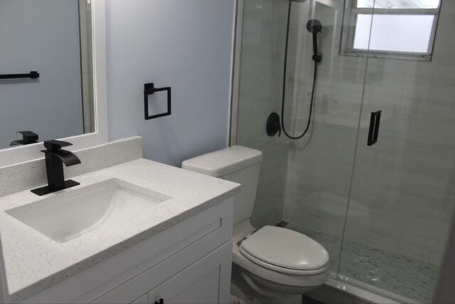 bathroom with vanity, toilet, and a shower with shower door