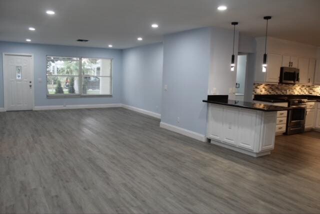 kitchen featuring dark wood-type flooring, white cabinets, pendant lighting, and appliances with stainless steel finishes