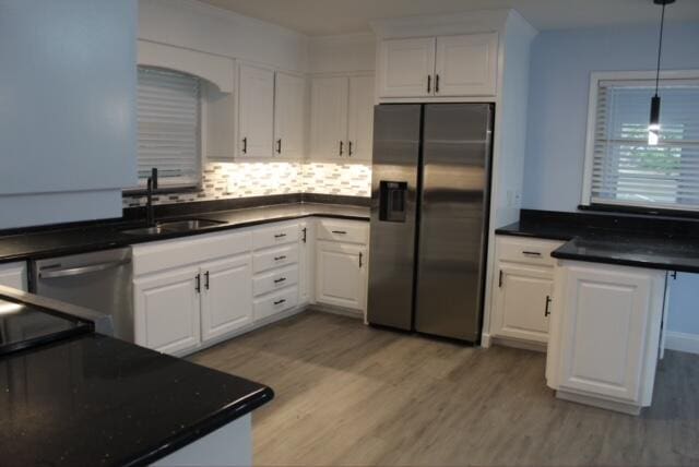 kitchen with appliances with stainless steel finishes, tasteful backsplash, sink, light hardwood / wood-style flooring, and white cabinetry