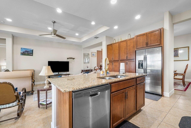 kitchen with sink, light stone counters, a textured ceiling, a kitchen island with sink, and appliances with stainless steel finishes