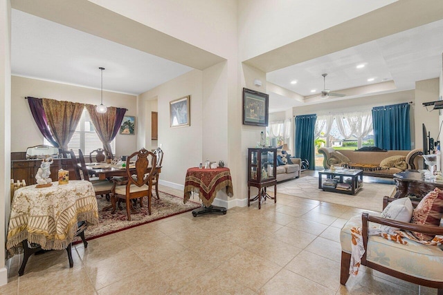 living room with plenty of natural light, ceiling fan, and a raised ceiling