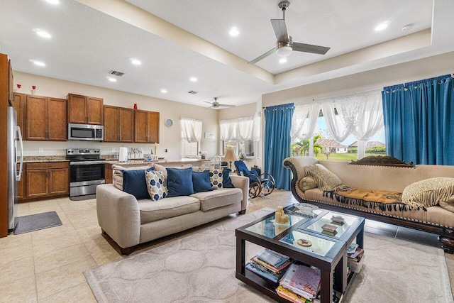 tiled living room with ceiling fan, a textured ceiling, and a tray ceiling