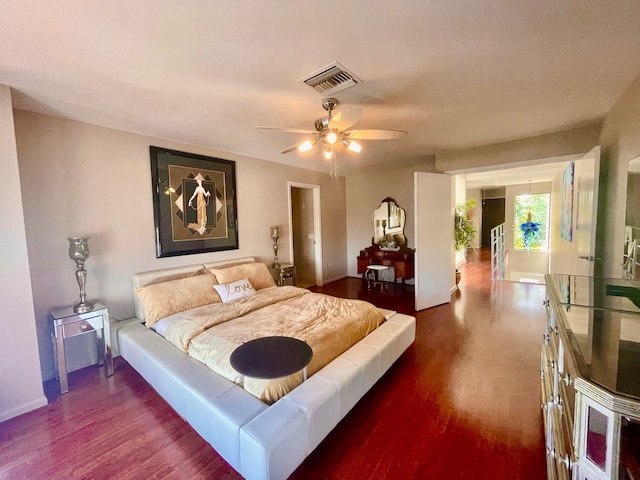 bedroom featuring a ceiling fan, visible vents, and wood finished floors