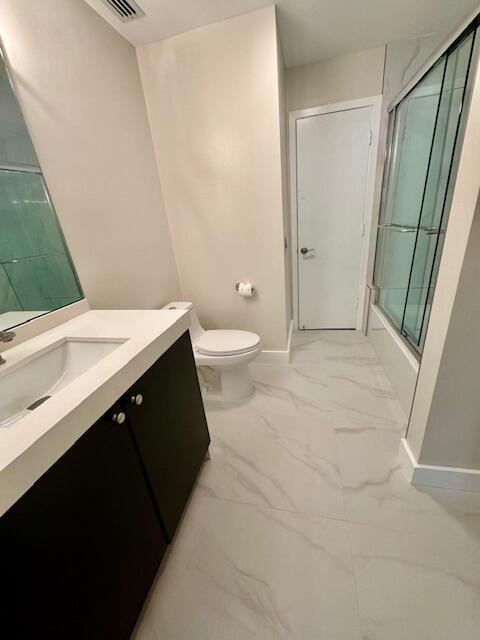 full bathroom featuring baseboards, toilet, enclosed tub / shower combo, marble finish floor, and vanity