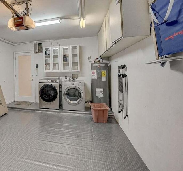 clothes washing area with a garage, laundry area, washer and clothes dryer, and electric water heater