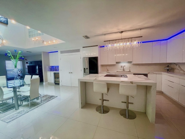 kitchen featuring pendant lighting, a center island, refrigerator with ice dispenser, and white cabinetry