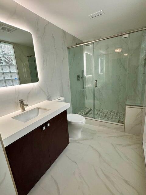 bathroom featuring a marble finish shower, visible vents, toilet, marble finish floor, and vanity