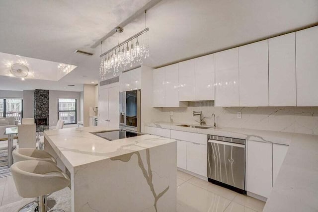 kitchen with a center island, stainless steel appliances, a kitchen bar, white cabinets, and sink