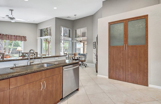 kitchen featuring dishwasher, sink, a healthy amount of sunlight, and dark stone countertops