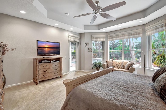 bedroom featuring multiple windows, a tray ceiling, and ceiling fan