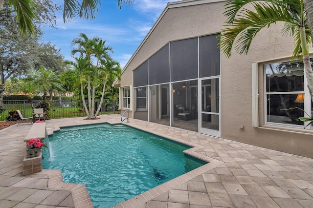 view of pool with a patio, pool water feature, and a sunroom