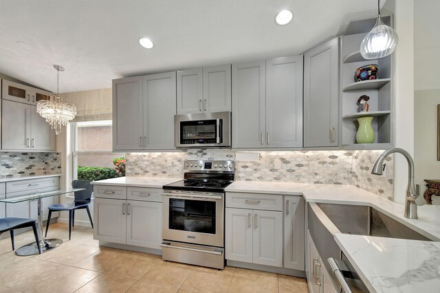 kitchen with light stone counters, stainless steel appliances, sink, gray cabinets, and lofted ceiling