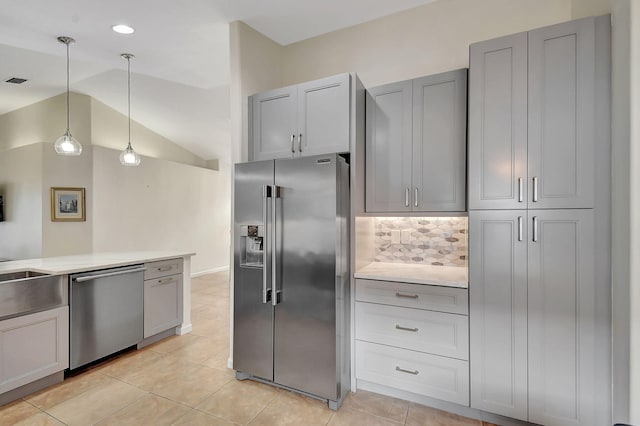 kitchen with gray cabinetry, backsplash, decorative light fixtures, lofted ceiling, and appliances with stainless steel finishes