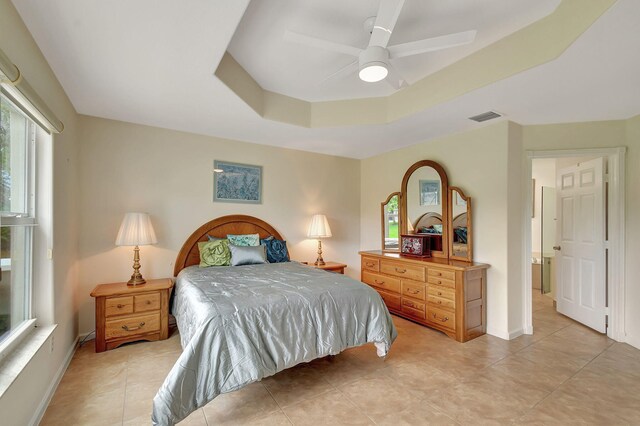 bedroom featuring a tray ceiling, ceiling fan, and light tile patterned floors