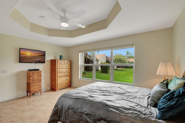 tiled bedroom featuring ceiling fan and a tray ceiling