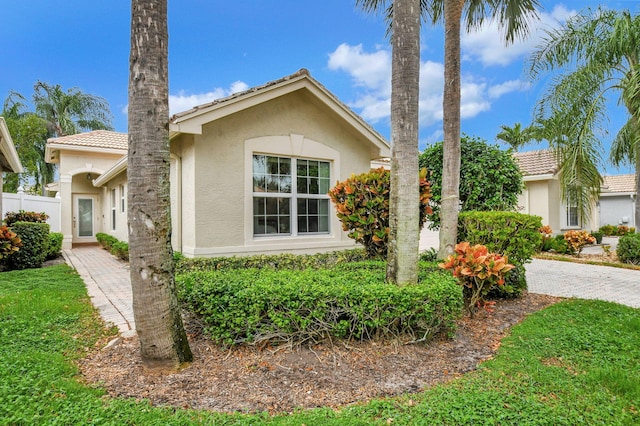 view of front of house featuring a tiled roof, fence, and stucco siding