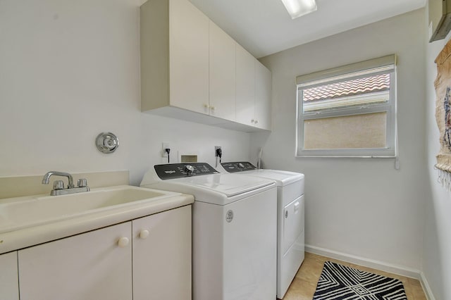 laundry area featuring washing machine and dryer, sink, light tile patterned flooring, and cabinets