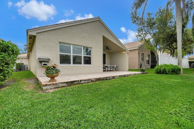 rear view of house with a patio area, ceiling fan, cooling unit, and a lawn