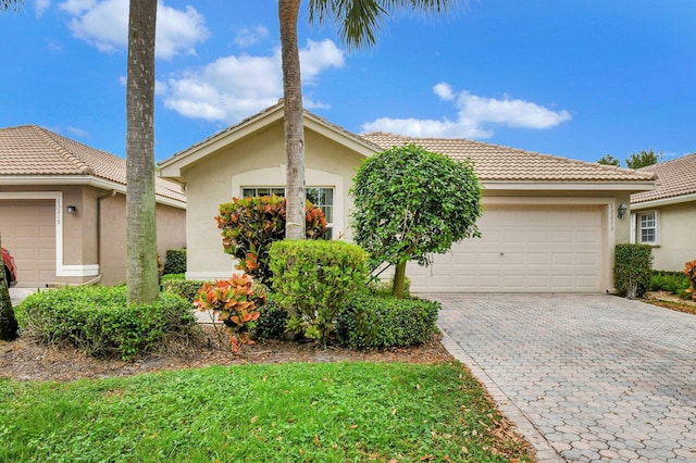 single story home featuring decorative driveway, a tile roof, an attached garage, and stucco siding