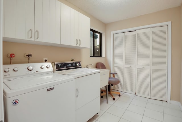 clothes washing area featuring washer and clothes dryer, cabinets, light tile patterned floors, and a textured ceiling