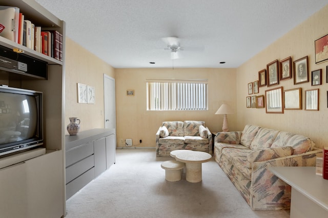 living room featuring ceiling fan, light colored carpet, and a textured ceiling