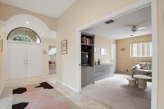 carpeted entrance foyer with ceiling fan, a healthy amount of sunlight, and a textured ceiling