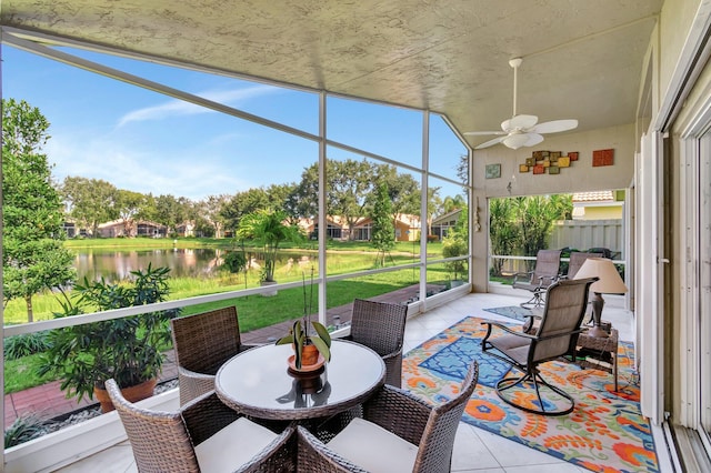 sunroom with ceiling fan and a water view