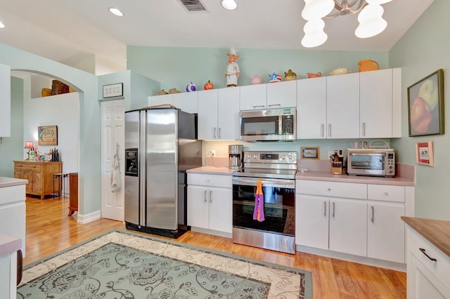 kitchen with white cabinetry, vaulted ceiling, and appliances with stainless steel finishes