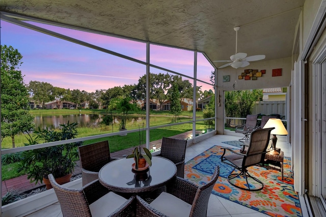 sunroom featuring a wealth of natural light, ceiling fan, and a water view