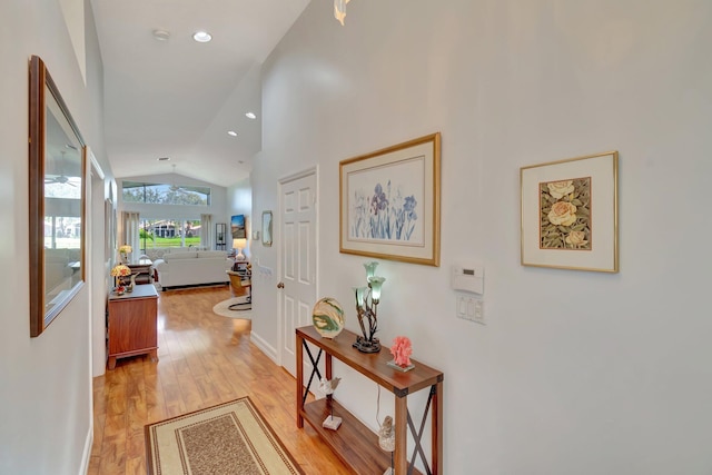 corridor with light hardwood / wood-style floors and lofted ceiling