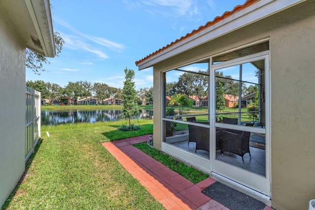 view of yard with a sunroom and a water view