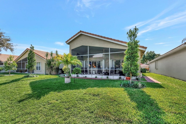 rear view of house featuring a sunroom and a yard