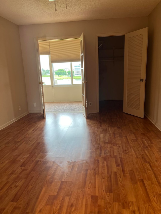 unfurnished bedroom featuring a closet, hardwood / wood-style floors, and a textured ceiling