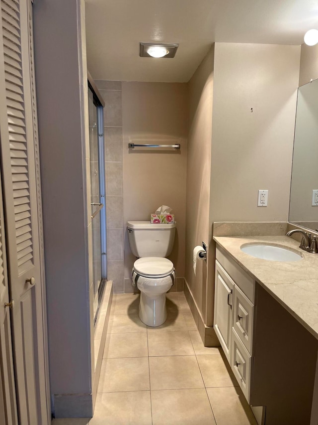 bathroom with tile patterned flooring, vanity, toilet, and walk in shower