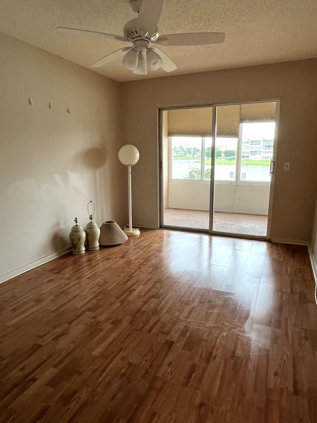 empty room with ceiling fan, wood-type flooring, and a textured ceiling