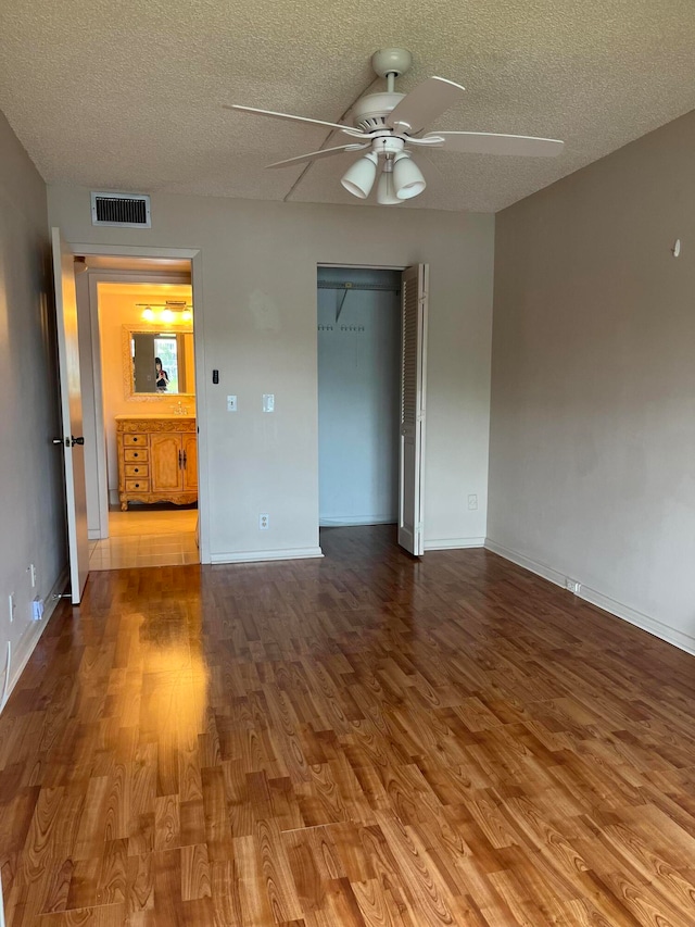 spare room with hardwood / wood-style flooring, ceiling fan, and a textured ceiling