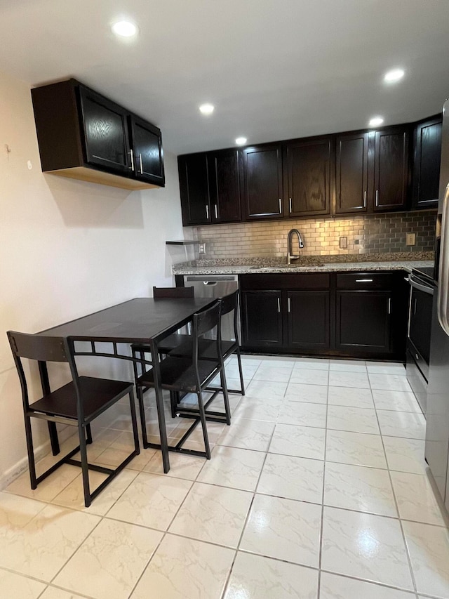 kitchen featuring light stone countertops, tasteful backsplash, stainless steel electric range oven, and sink