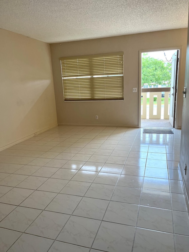 unfurnished room with light tile patterned floors and a textured ceiling